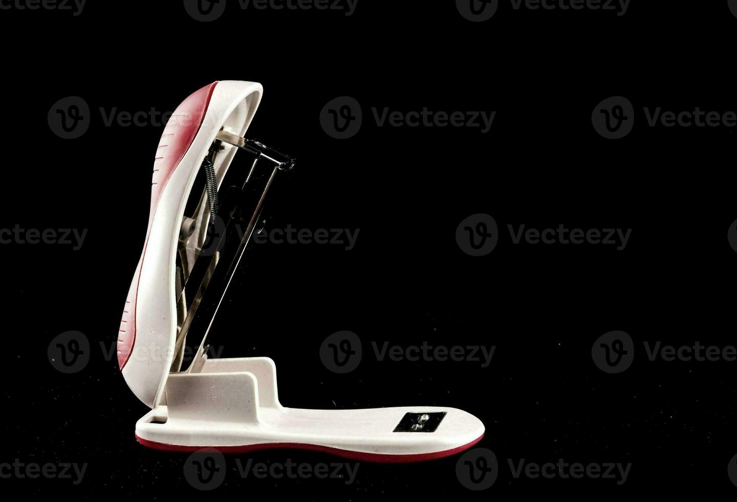 a white and red stapler on a black background photo