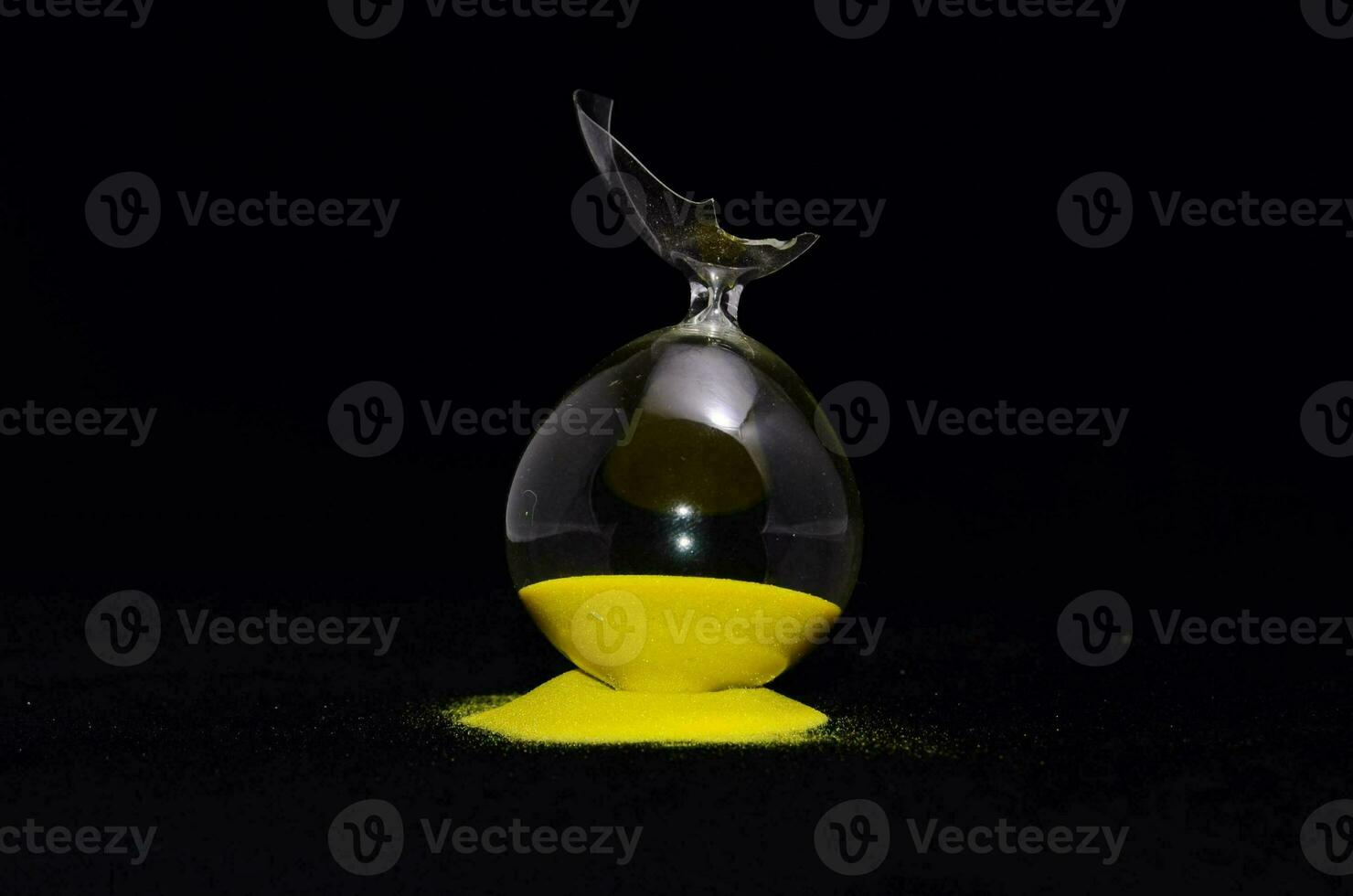 a broken hourglass on black background photo