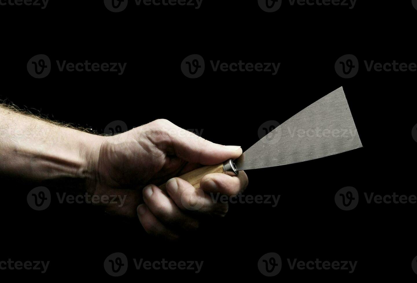 a man's hand holding a knife on a black background photo