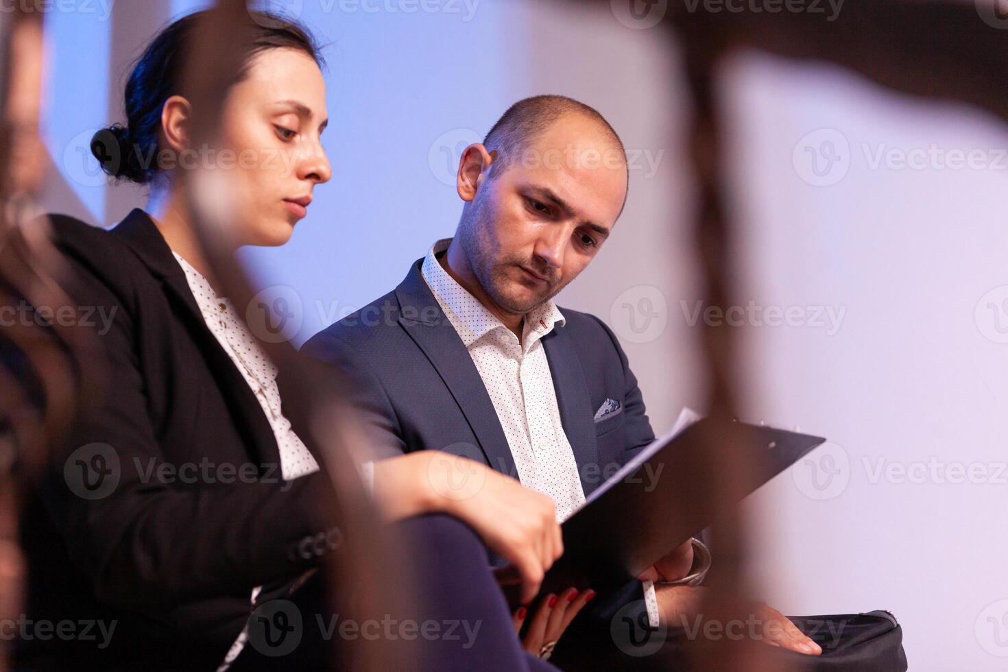 Businessman doing overtime with businesswoman late night afterhours tired on a deadline. Colleague entrepreneur working late together in evening at corporate job sitting on staircase, explaining difficult finance project. photo