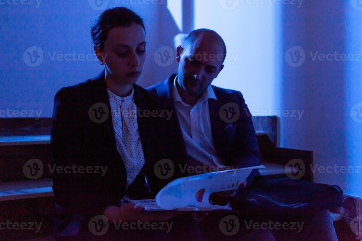 Stressed tired businesswoman helping coworker with deadline doing overtime. Colleague entrepreneur working late together in evening at corporate job sitting on staircase, explaining difficult finance project. photo