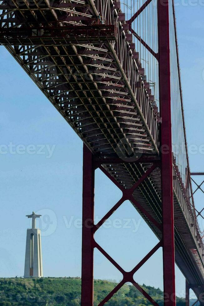 the bridge is red and has a statue on top photo