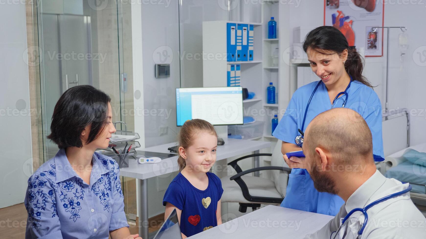 Doctor and nurse talking with child patient sitting at desk in medical office. Healthcare physician specialist in medicine providing health care services radiographic treatment examination in hospital photo