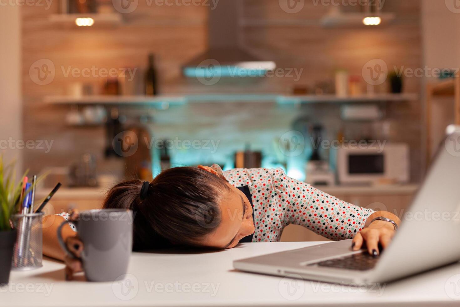 Woman falling asleep with head on the table while working from home on a deadline. Employee using modern technology at midnight doing overtime for job, business, career, network, lifestyle ,wireless. photo