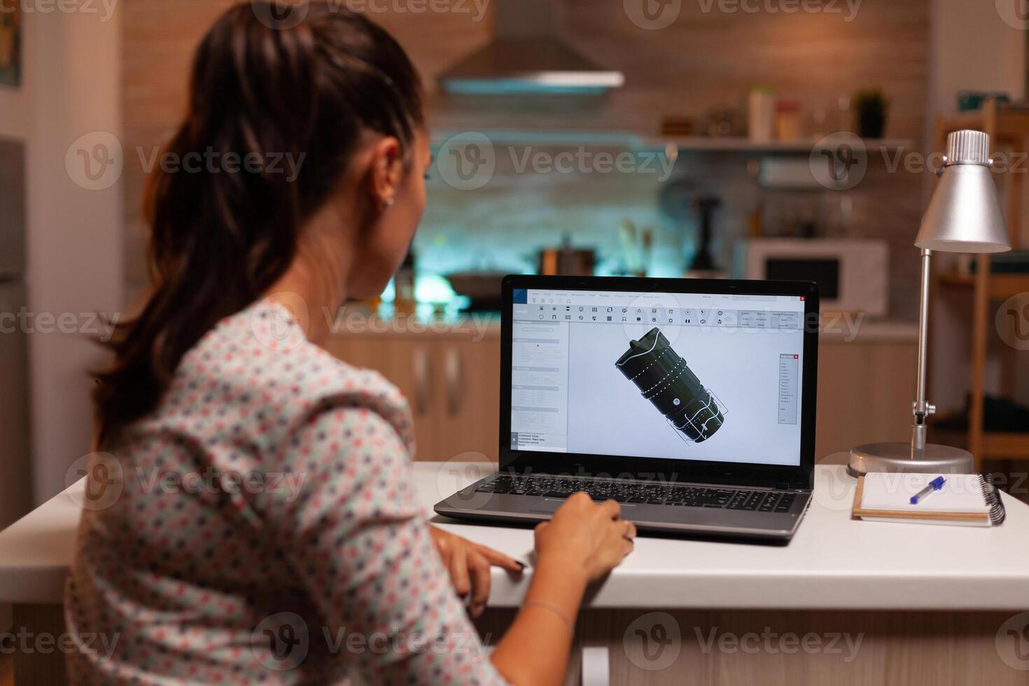 Back view of engineer working on turbine project in home office during night time. Industrial female engineer working on personal computer showing cad software. photo