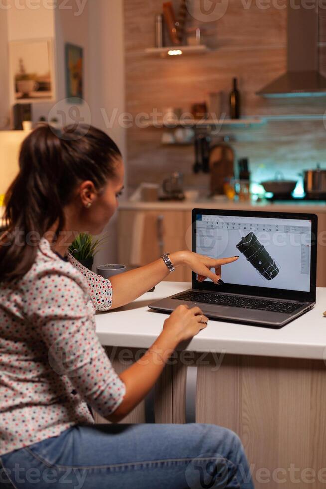 Engineer pointing at turbine project on laptop while working on laptop during night time. Industrial female engineer working on personal computer showing cad software. photo