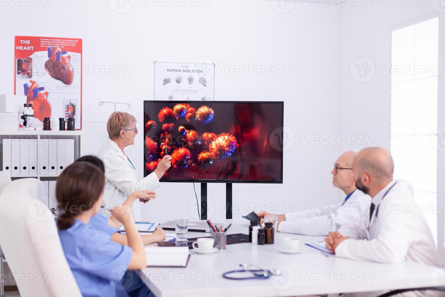 Medical colleagues discussing about coronavirus during meeting in conference room. Virolog specialist doctor discussing with colleagues about global pandemic because of dangerous virus, symptoms. photo