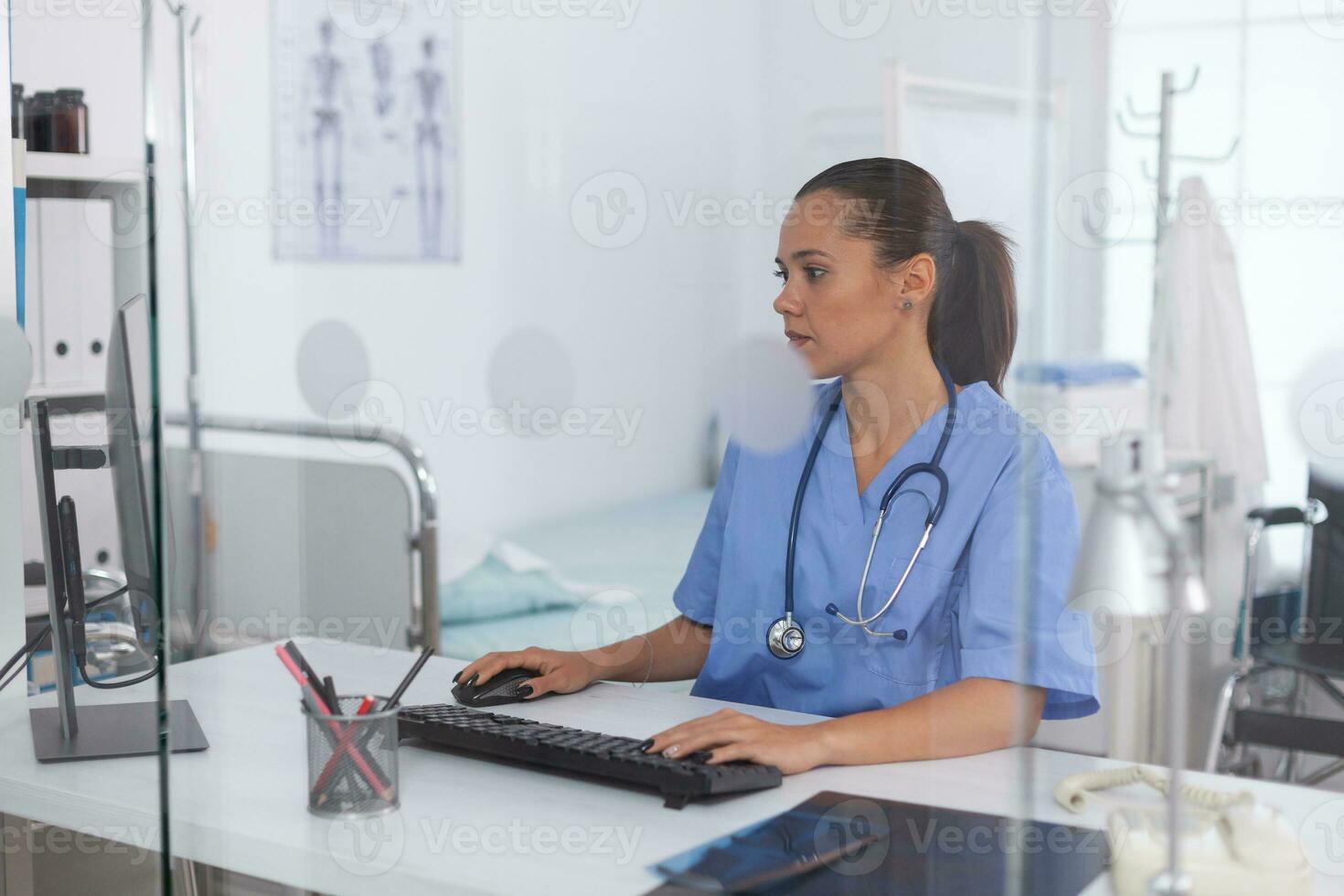 Medical practitioner using computer in hospital office. Health care physician using computer in modern clinic looking at monitor, medicine, profession, scrubs. photo