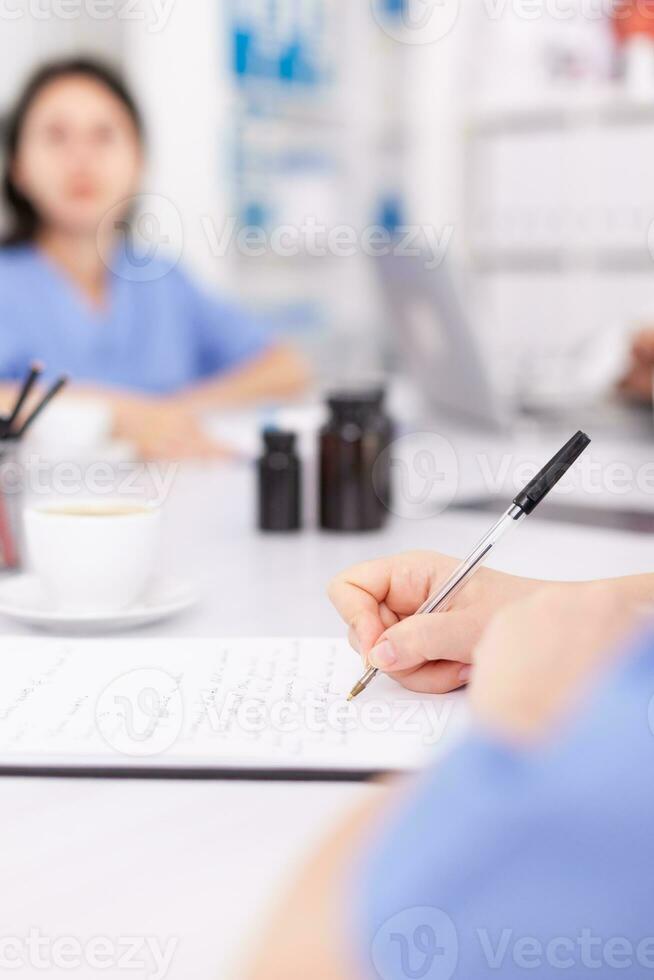 médico enfermero escritura en portapapeles durante cuidado de la salud seminario en hospital reunión oficina acerca de tecnología. clínica experto terapeuta hablando con colegas acerca de enfermedad, medicina profesional. foto