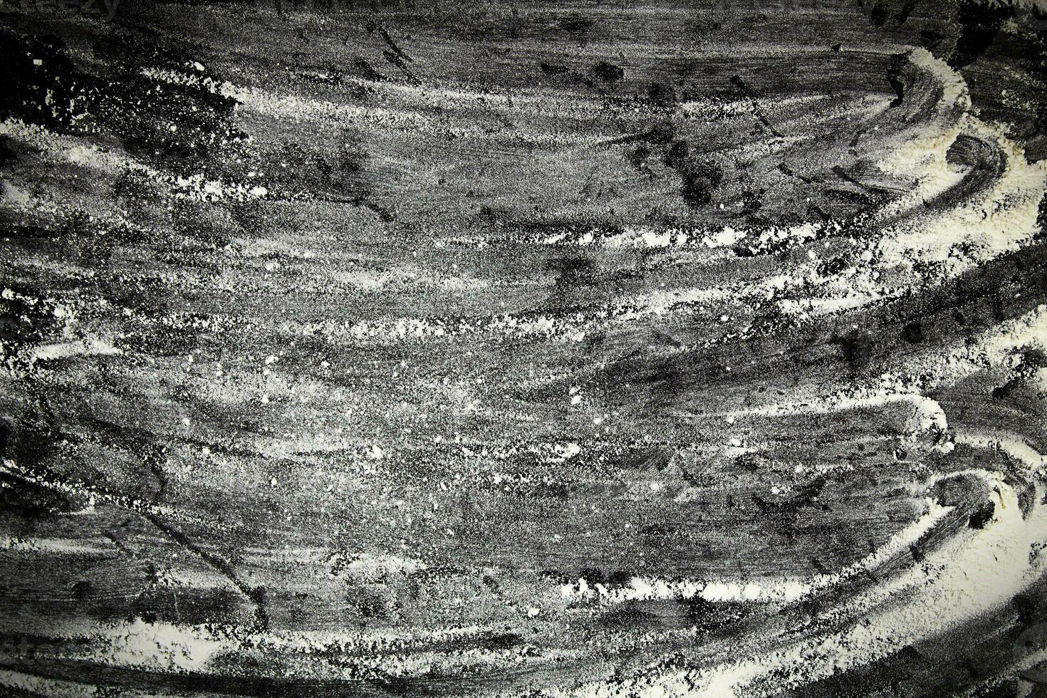 Flour is scattered on a black table. The concept of a bakery for baking homemade bread. photo
