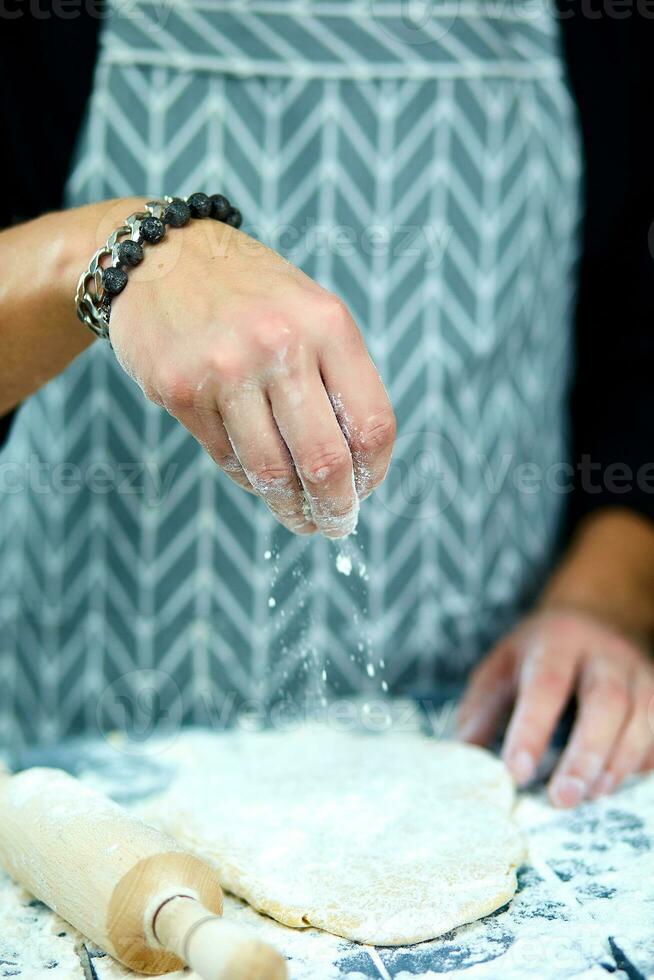 The chef cooks the dough sprinkled with flour freezing in motion photo