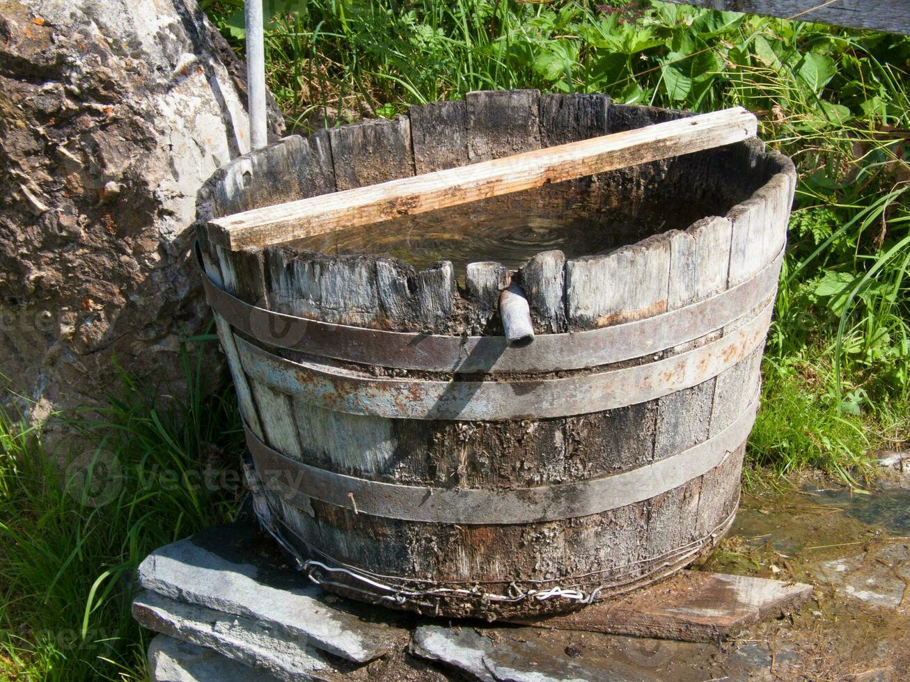 a wooden bucket sitting on a rock photo