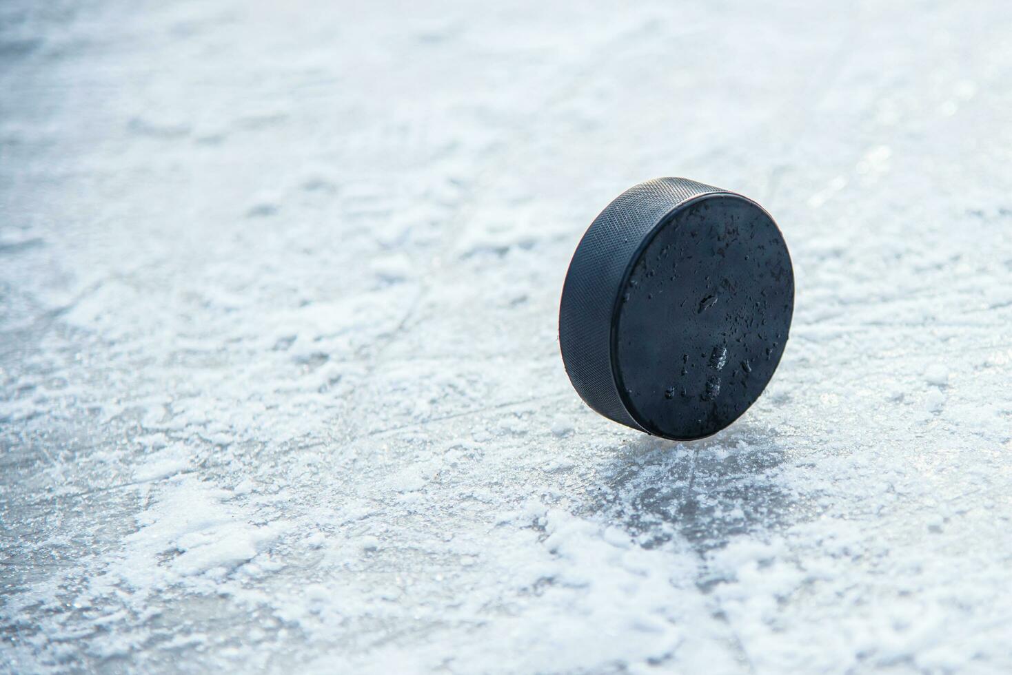 black hockey puck lies on ice at stadium photo