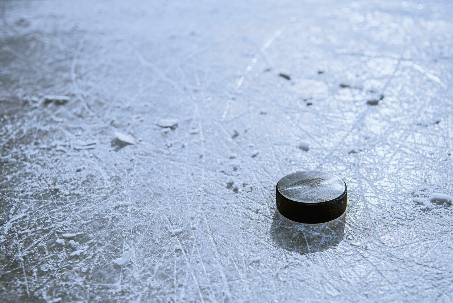 black hockey puck lies on ice at stadium photo