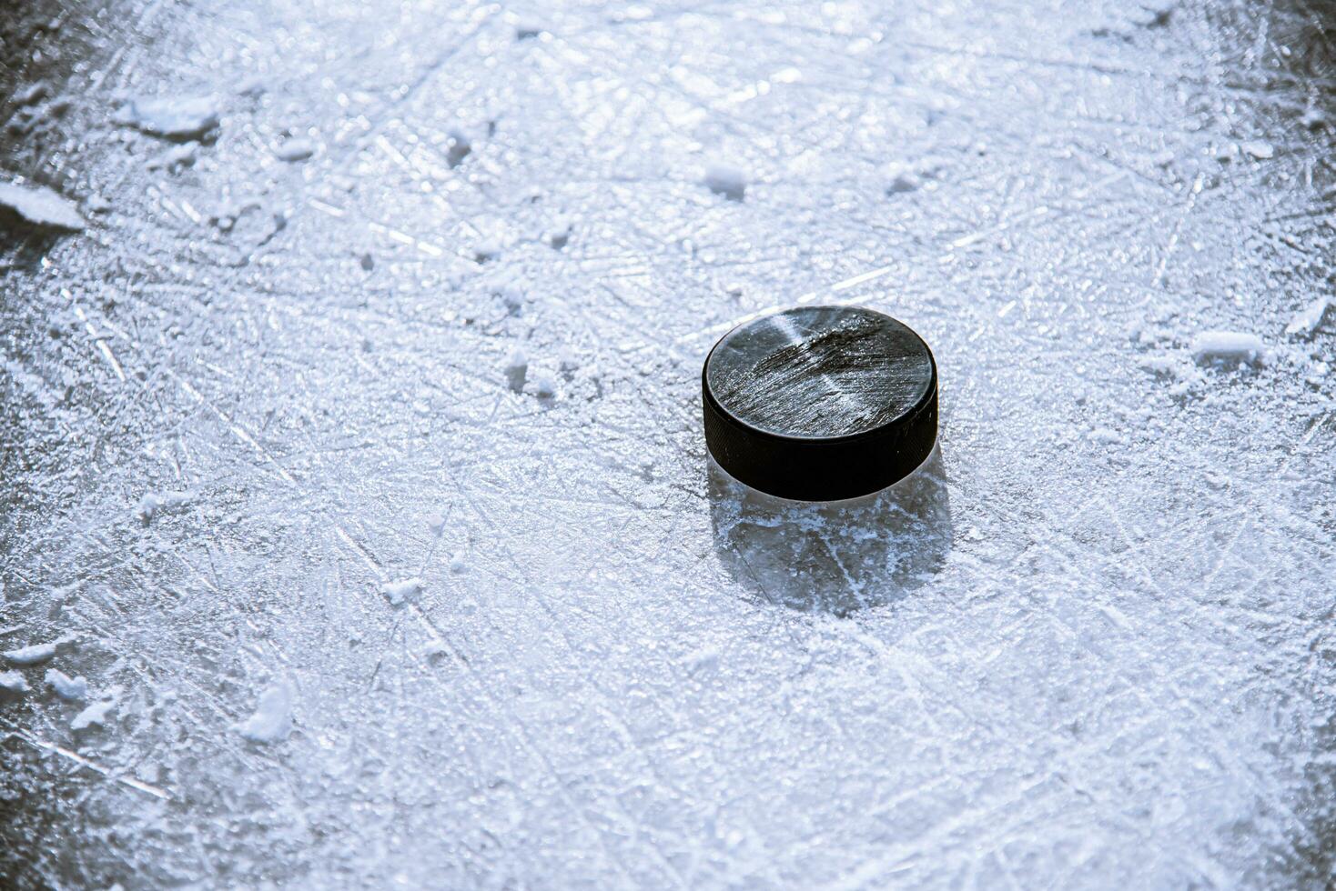 black hockey puck lies on ice at stadium photo