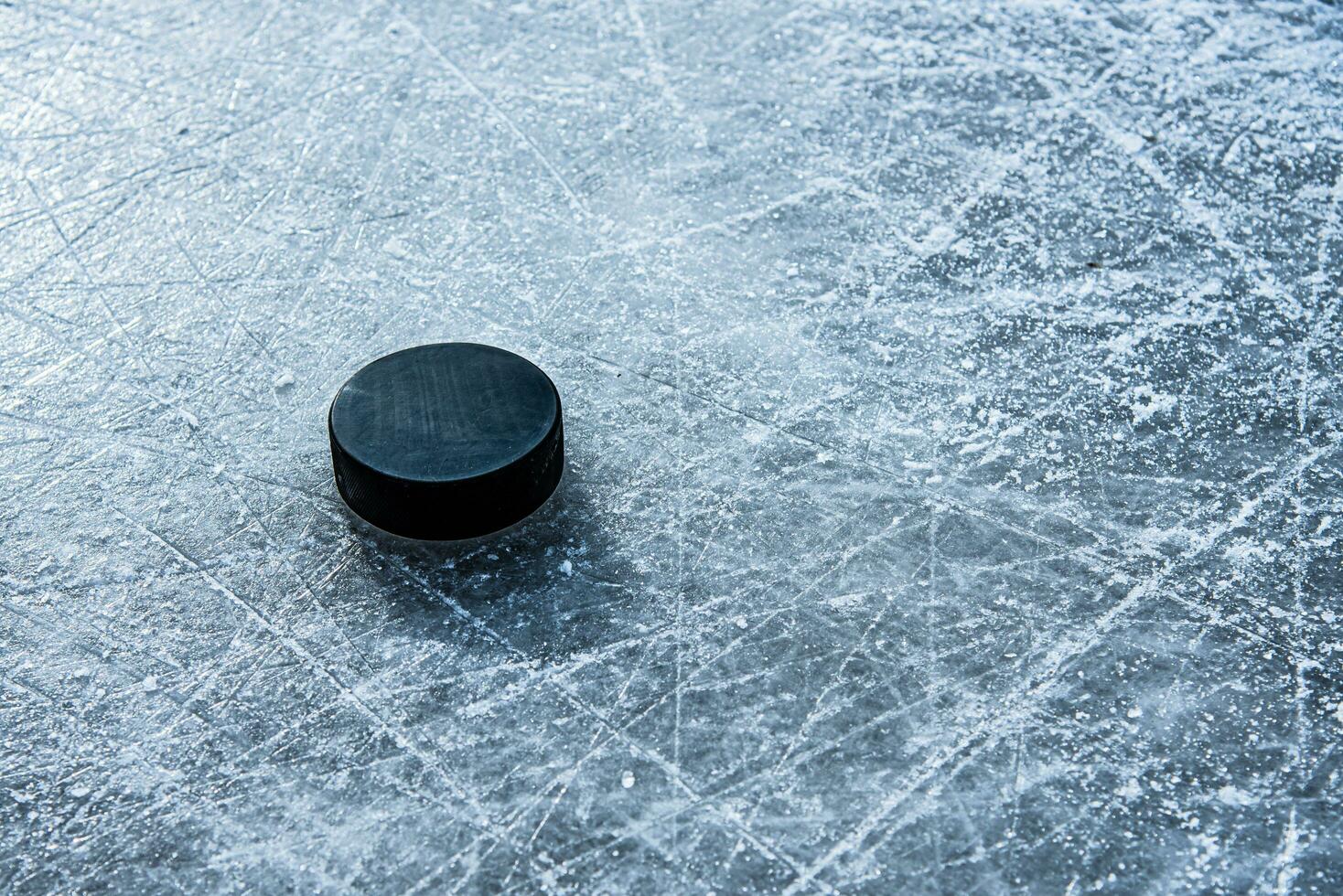 black hockey puck lies on ice at stadium photo
