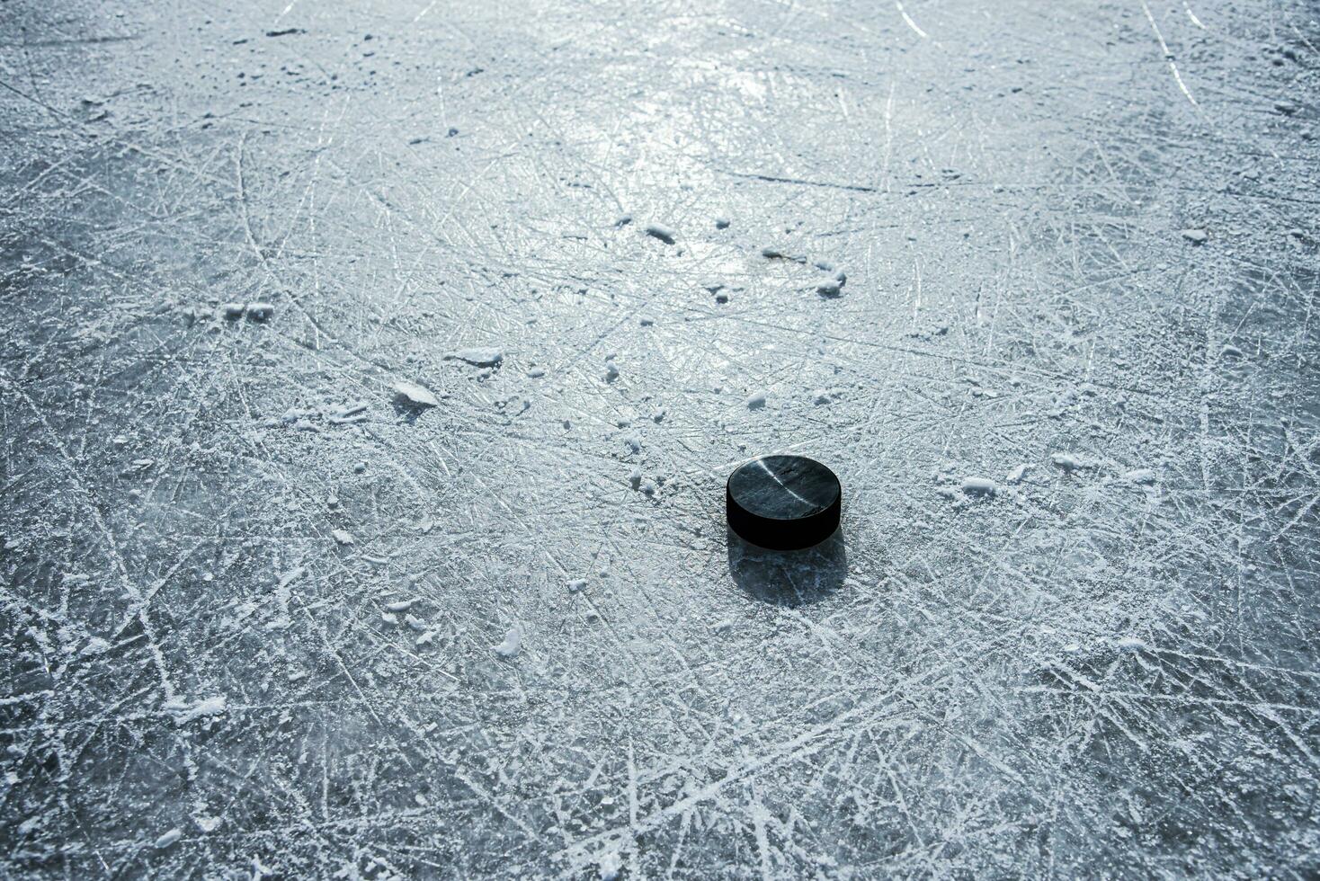 black hockey puck lies on ice at stadium photo