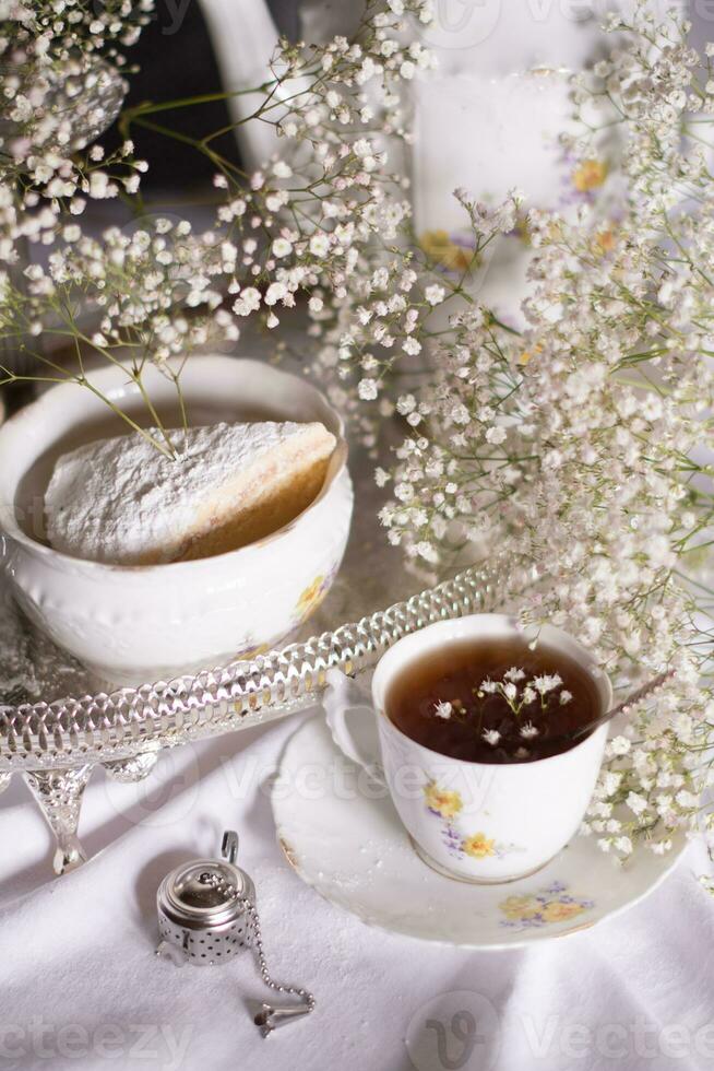 blanco todavía vida con tarta de queso y Gypsophila y taza de té, ligero y aireado foto