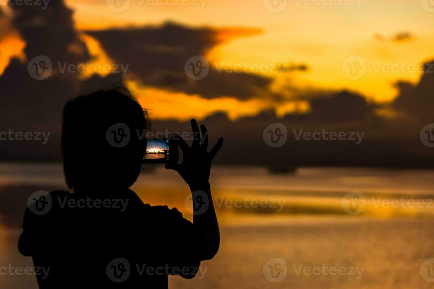 Silhouettes people shooting the sunset at the lake. photo