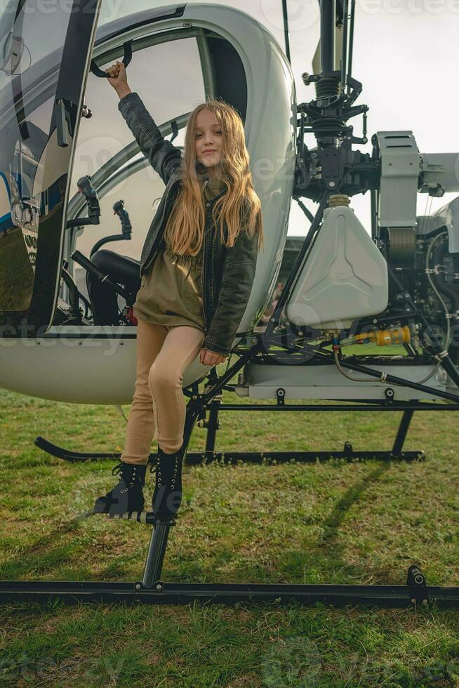 Cute preteen girl standing on footboard of open helicopter photo