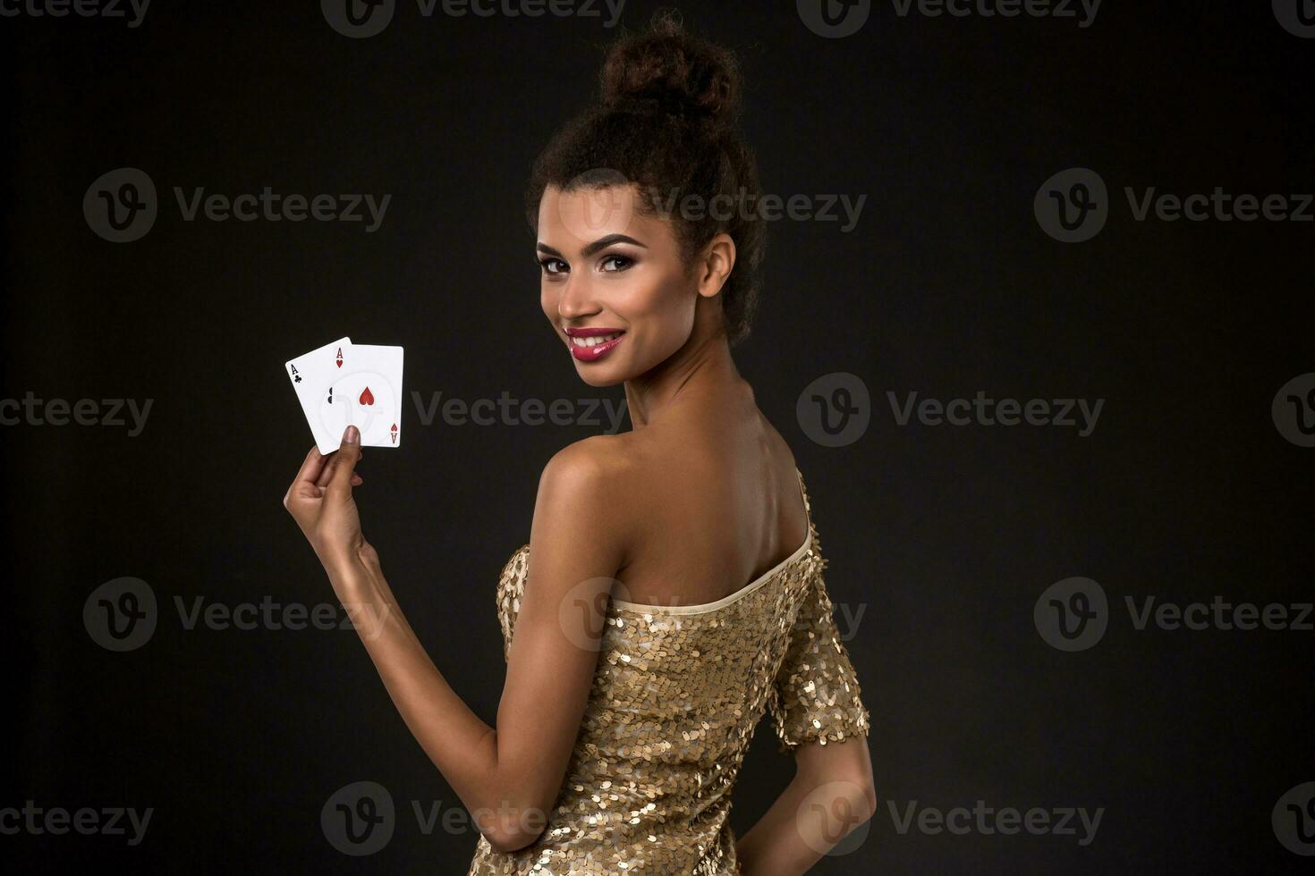 Woman winning - Young woman in a classy gold dress holding two aces, a poker of aces card combination. photo