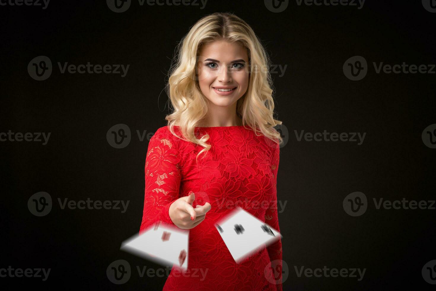 Young beautiful emotional woman throws cards on a black background in the studio. Poker photo