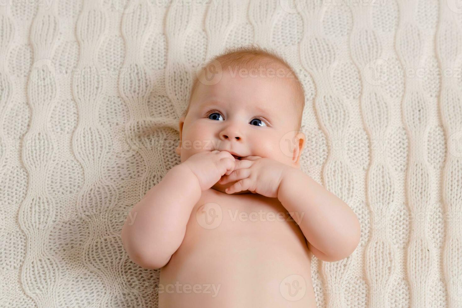 Happy baby lying on a white plaid in the bedroom photo