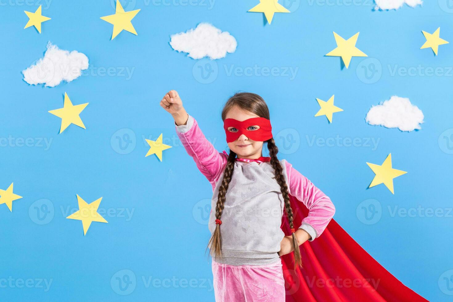 Little child plays superhero. Kid on the background of bright blue wall. photo