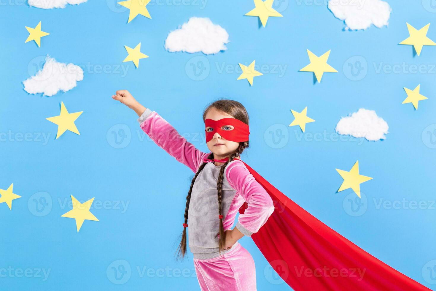 Little child plays superhero. Kid on the background of bright blue wall. photo
