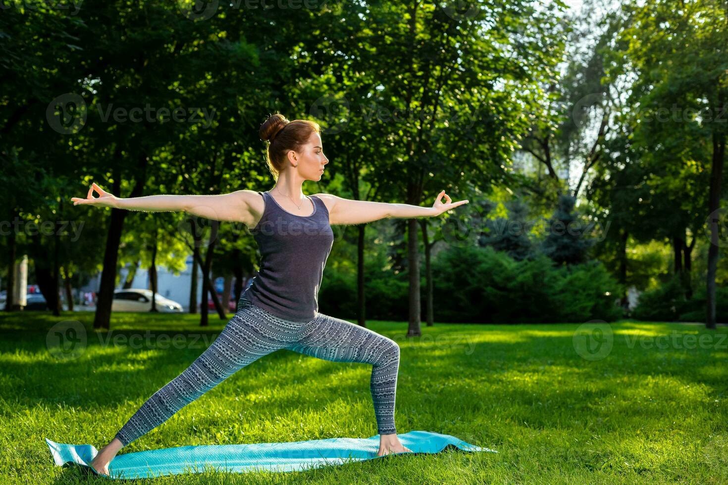 Young woman doing yoga exercises in the summer city park. photo