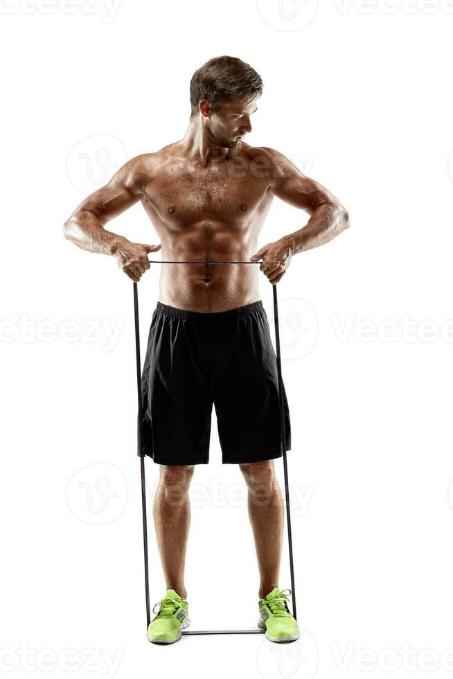 Handsome fitness man working out with rubber band, studio shot. photo