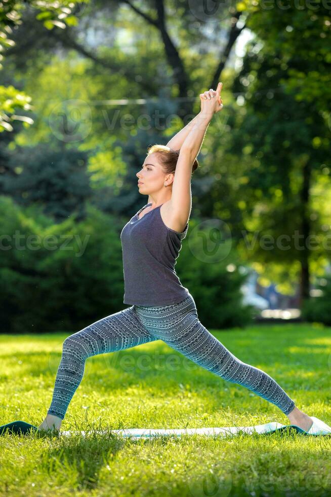 Young woman doing yoga exercises in the summer city park. photo