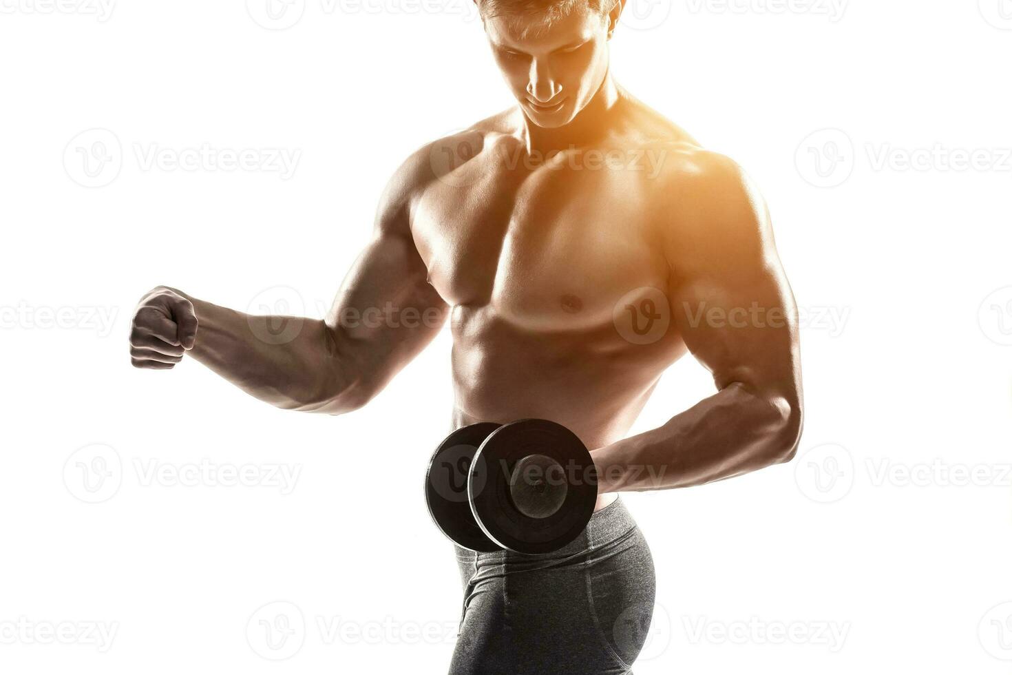 Athletic man showing muscular body and doing exercises with dumbbells photo