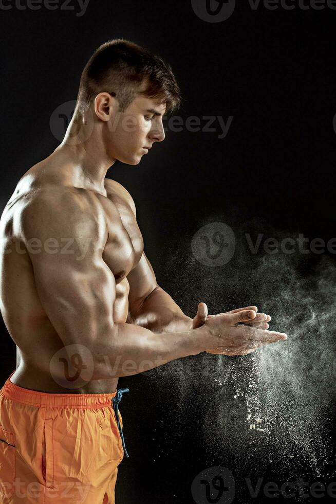 Preparing hands for lifting weights. White talcum dynamically scatters in different directions photo