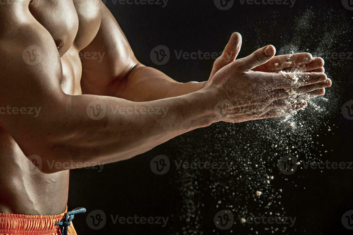 Preparing hands for lifting weights. White talcum dynamically scatters in different directions photo