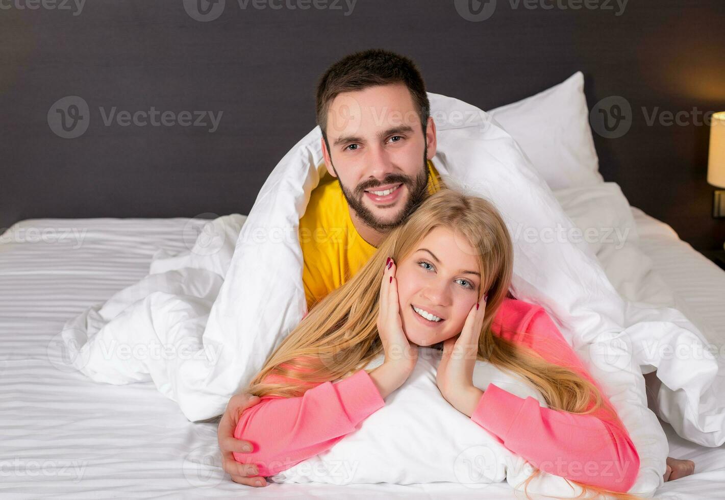 Young lovely couple lying and have fun in a bed photo