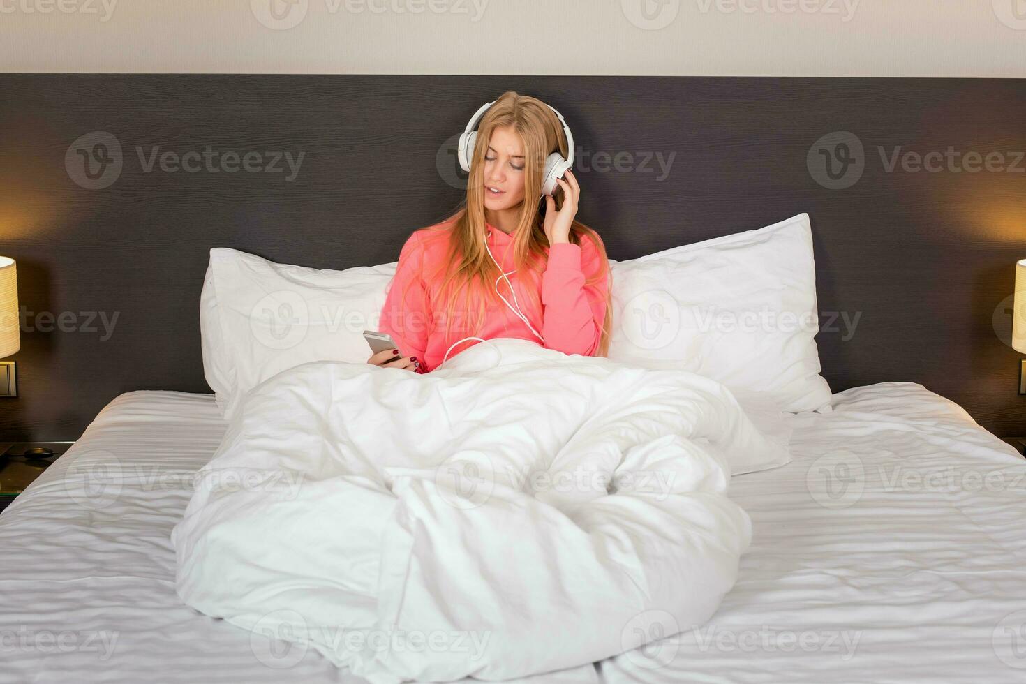 Young women listening to the music from smartphone on bed photo