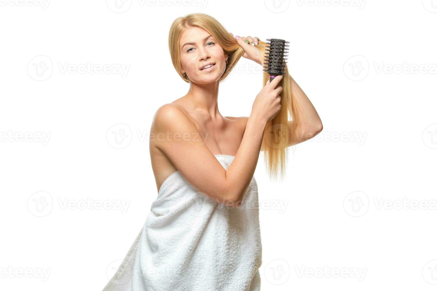 joven mujer en un toalla cepillado su cabello. foto
