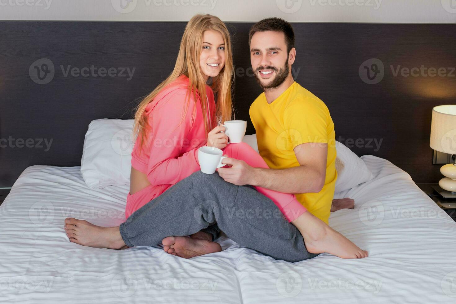 Happy young couple having breakfast tray on bed at home photo