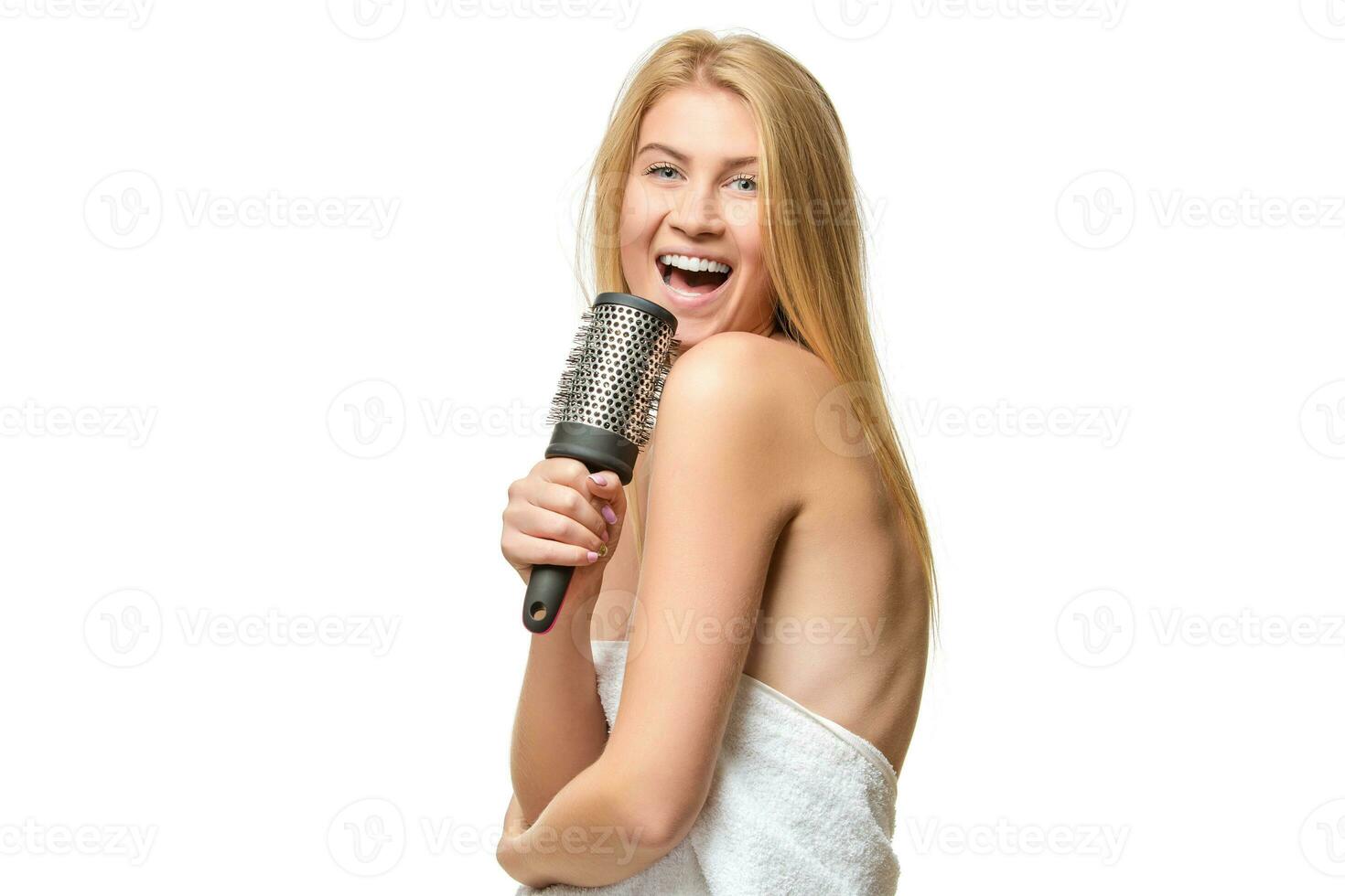 Happy woman in towel singing using comb photo