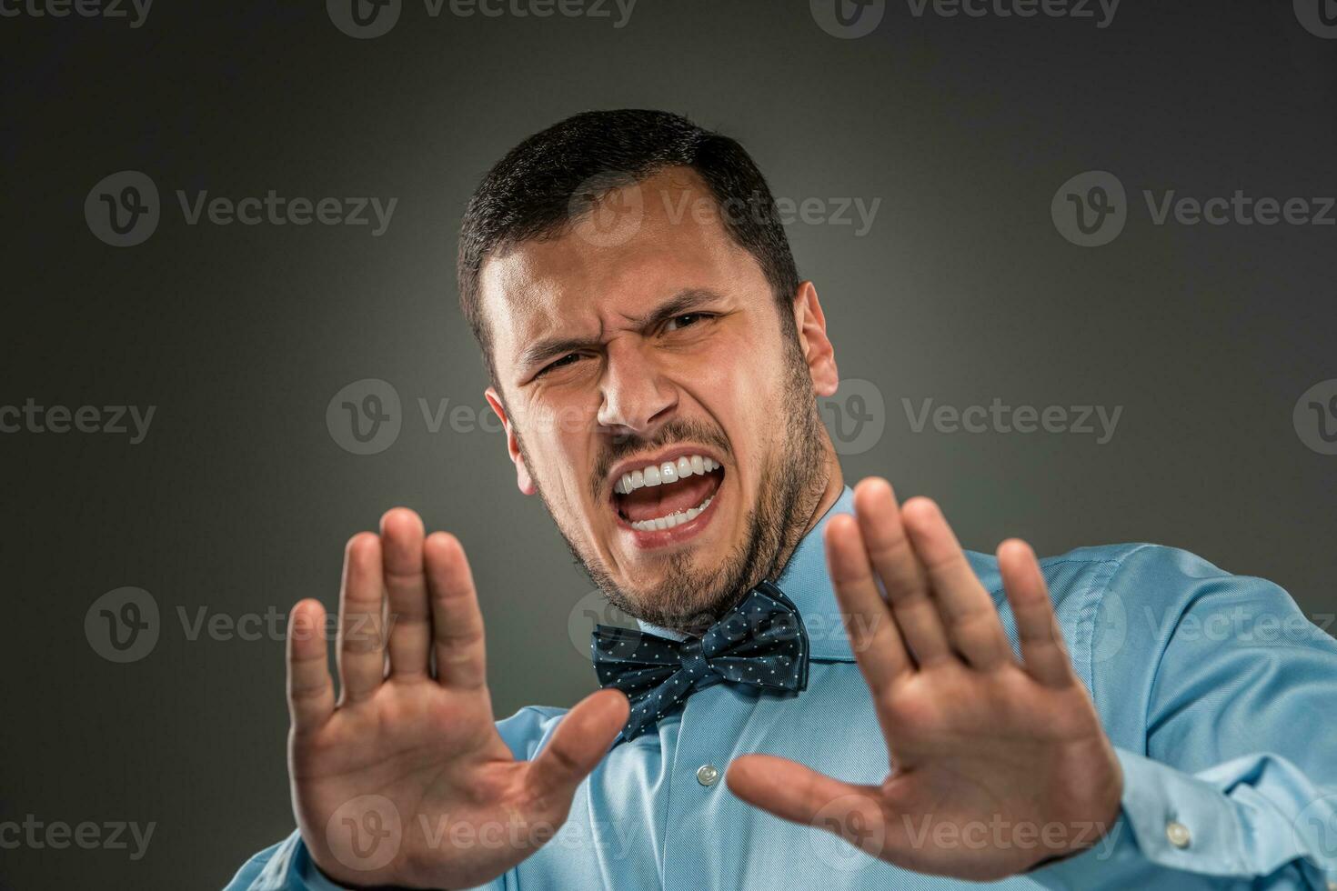 Portrait angry upset young man in blue shirt, butterfly tie photo