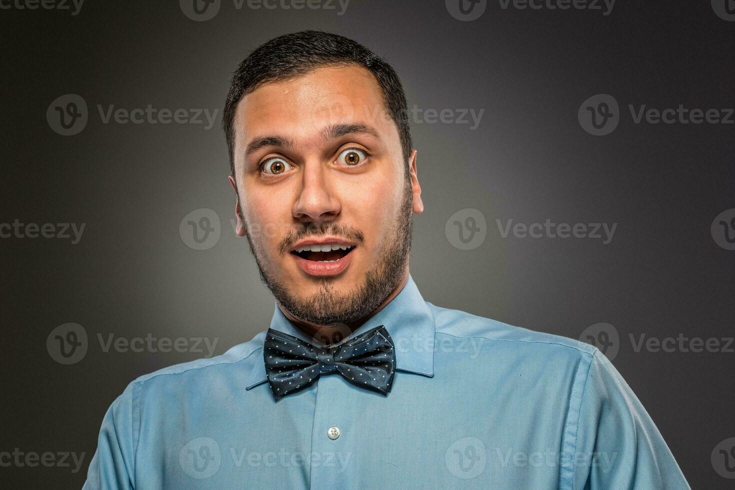 Portrait young man in blue shirt, looking with amazement photo