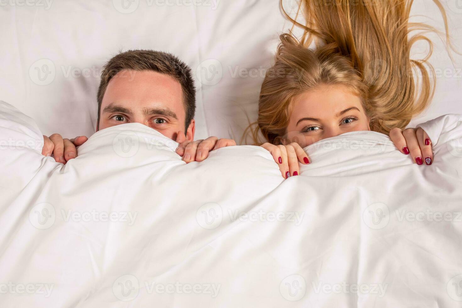 Young lovely couple lying in a bed, looking at camera photo