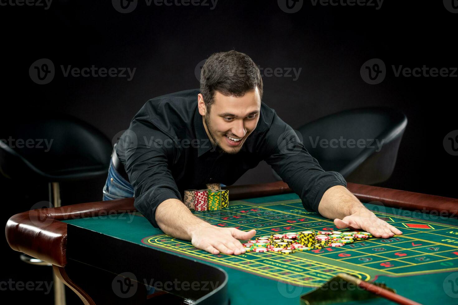 Young handsome man playing roulette wins at the casino photo