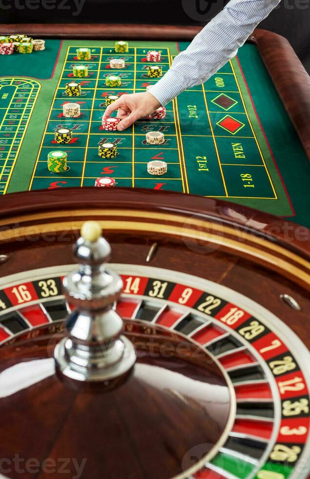 Roulette and piles of gambling chips on a green table. photo