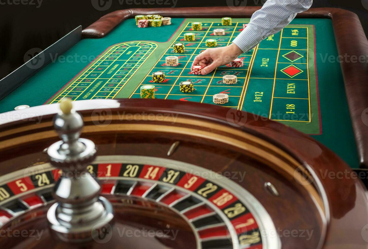 Roulette and piles of gambling chips on a green table. photo