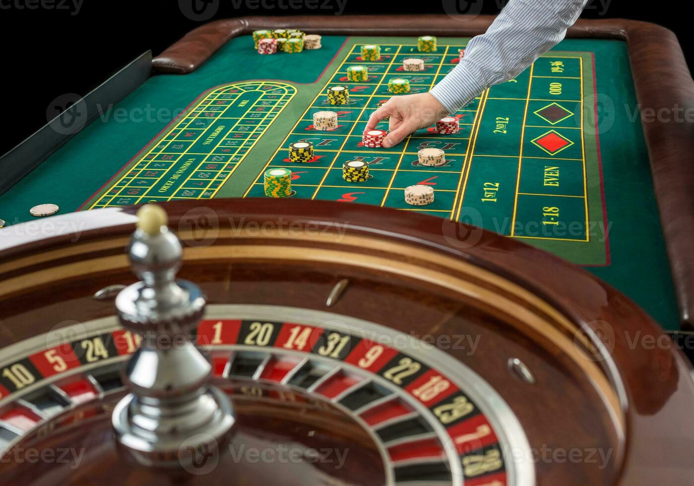Roulette and piles of gambling chips on a green table. photo