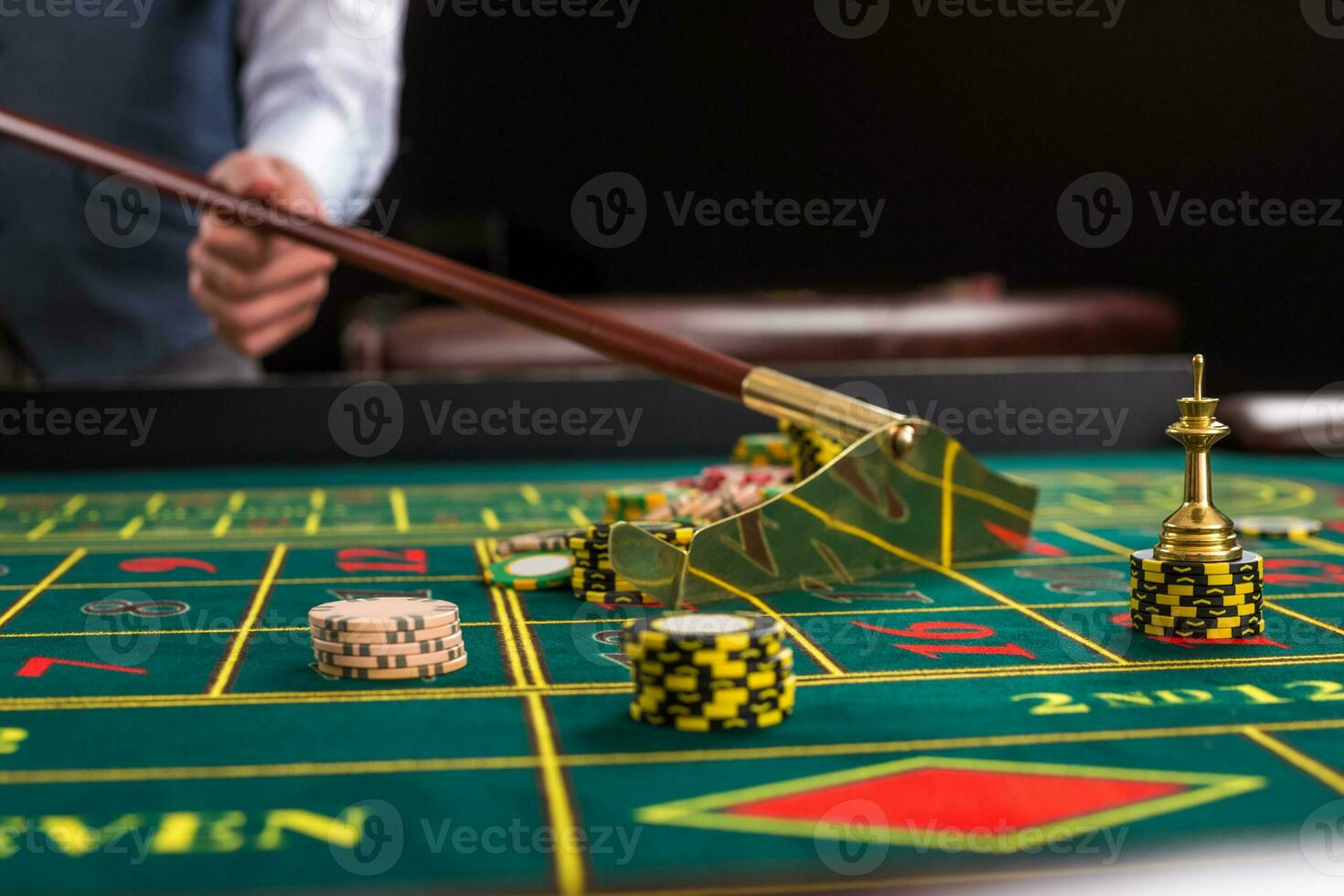 Croupier collects chips using stick in casino. photo