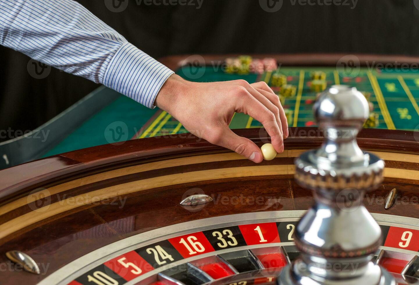 Roulette wheel and croupier hand with white ball in casino photo