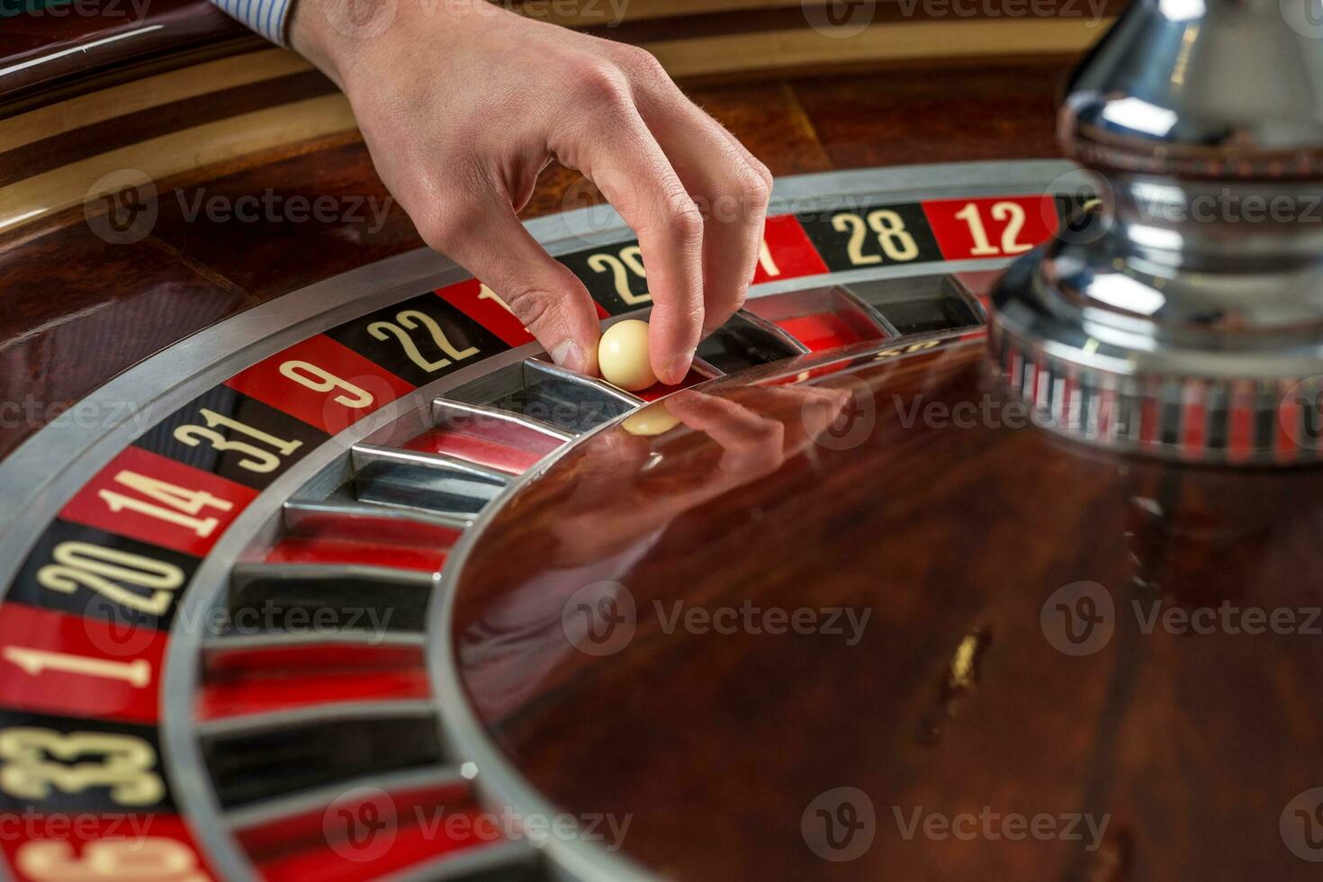 Roulette wheel and croupier hand with white ball in casino photo